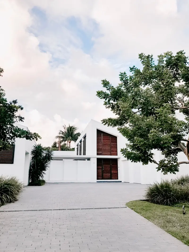 White gated home with timber screens and a paved motor court