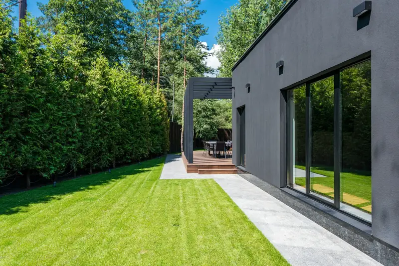 Charcoal single-level home with floor-to-ceiling glass beside a manicured lawn