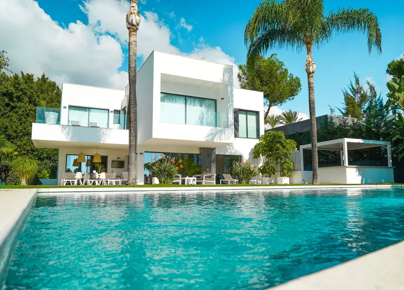White contemporary villa with palms beside a long swimming pool