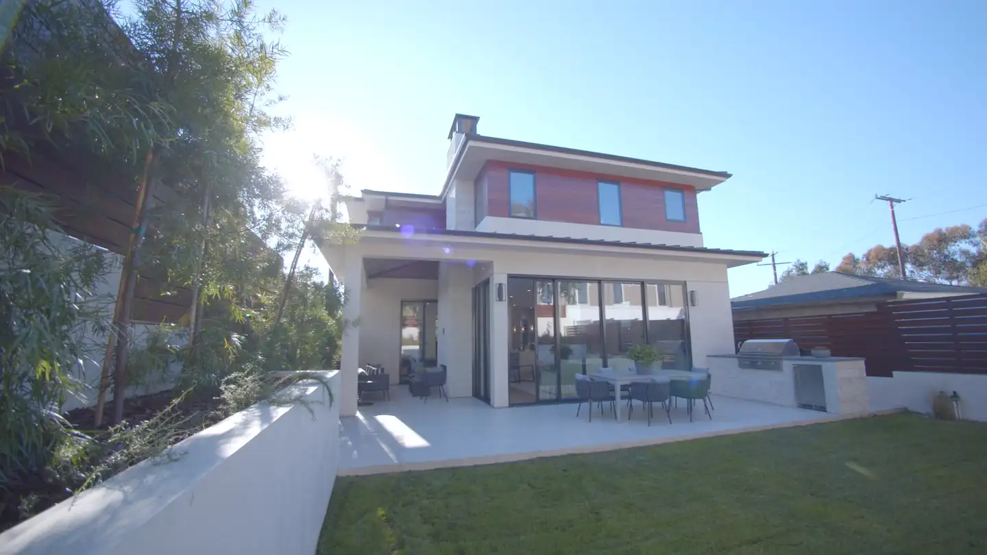 The landscaped rear patio of a modern Santa Monica home, with a covered loggia and walls of glass